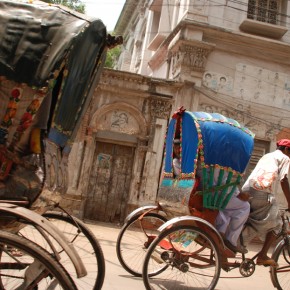 Rickshaw drivers pass historic buildings in Old Dhaka