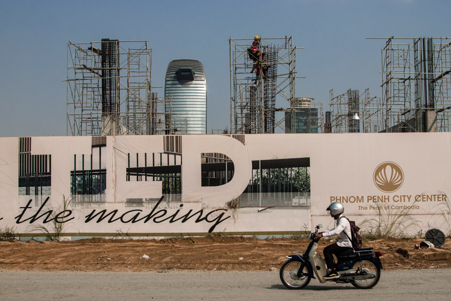 A motorbike drives past a new housing development under construction in Phnom Penh's Boeung Kak area.